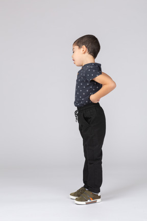 Side view of a sleepy boy standing with hands on back