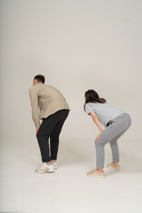 Young man and woman squatting with hands on knees