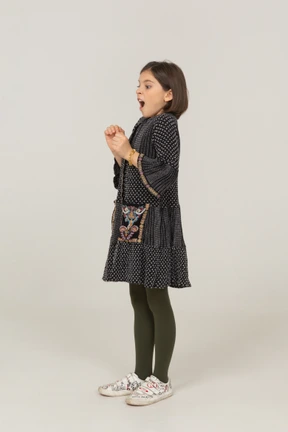 Side view of an excited little girl in dress clenching fists