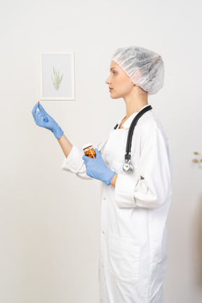 Vista lateral de una joven doctora ofreciendo una pastilla