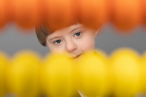 Little boy looking at camera through yellow and orange beads
