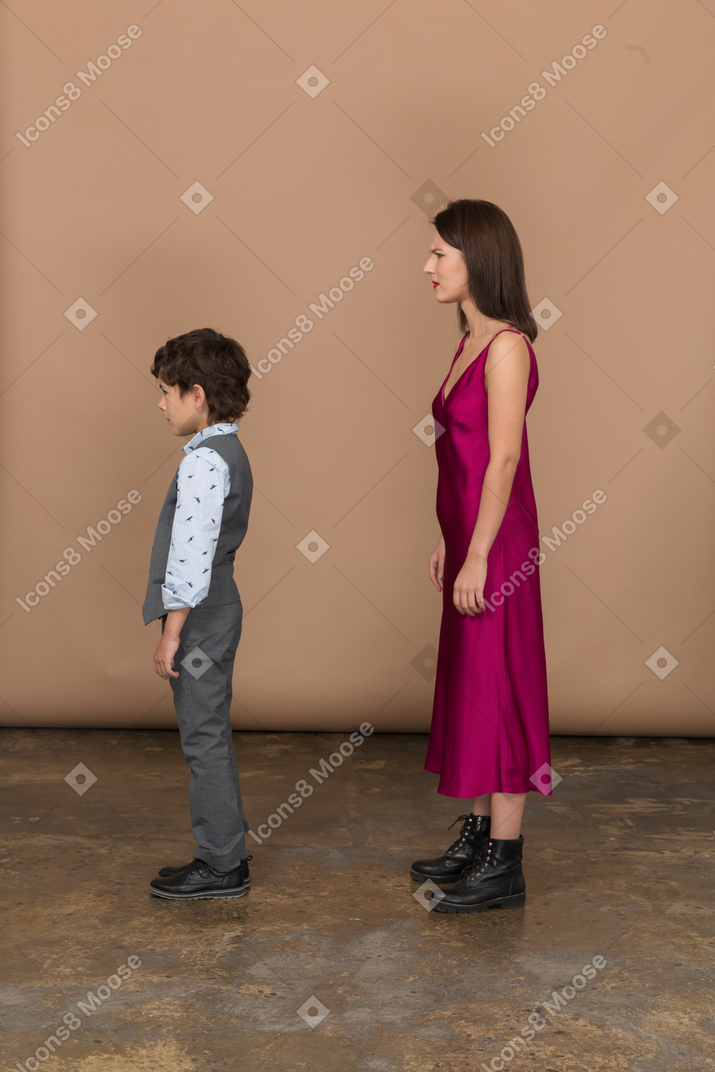 Donna delusa in abito rosso con ragazzo in piedi di profilo