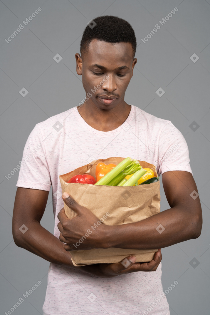 食料品の袋を保持している若い男