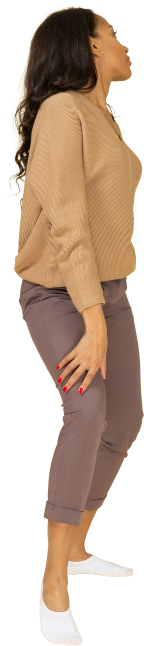 Vista lateral de una joven de piel oscura poniendo la mano en la cadera mientras mira a un lado