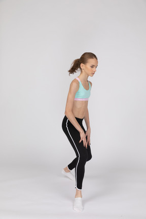 Three-quarter view of a teen girl in a sportswear making a lunge