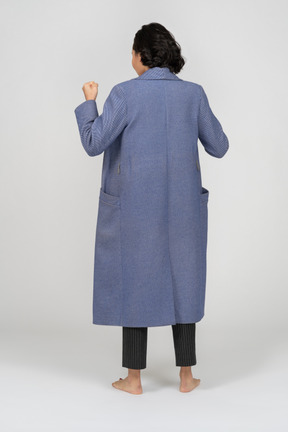 Back view of a woman in coat with raised fist