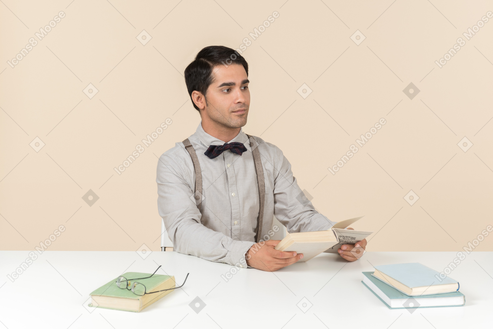 Профессор сидит за столом и читает книги