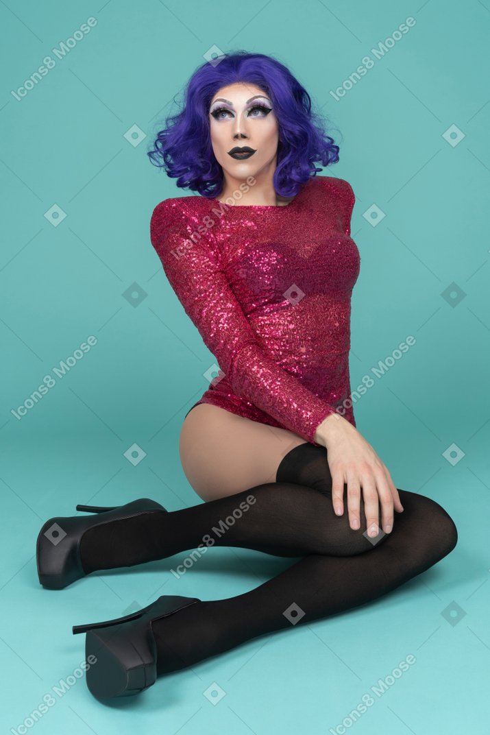 Portrait of a drag queen in pink dress sitting on the floor with hand on their knee