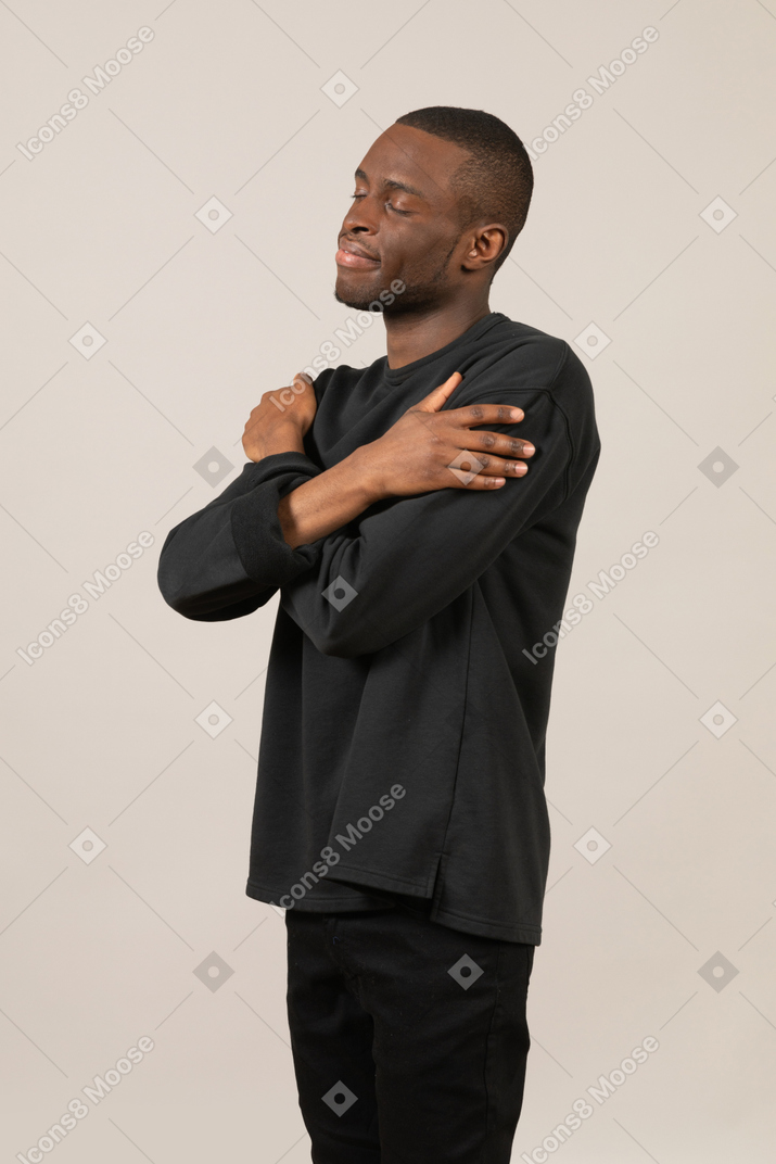 Hombre vestido de negro abrazándose a sí mismo