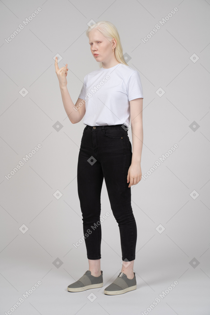 Vista di tre quarti di una giovane ragazza in piedi con le corna della mano