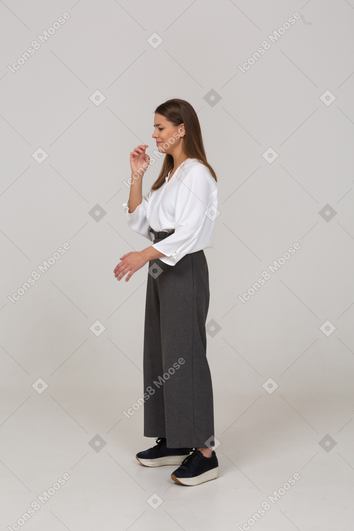 Трехчетвертный вид недовольной молодой леди в офисной одежде, машущей рукой