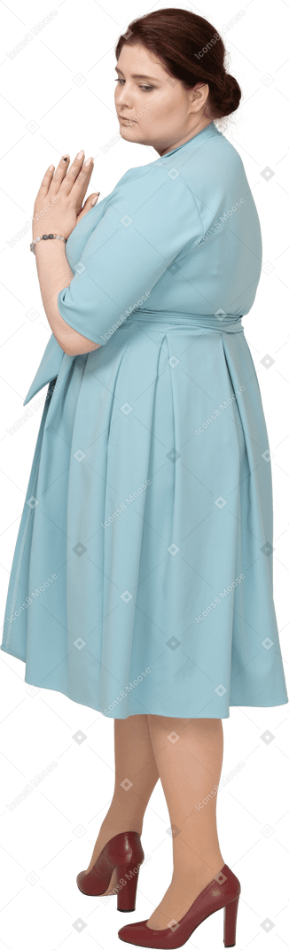 기도 제스처를 만드는 파란 드레스에 여자의 측면보기