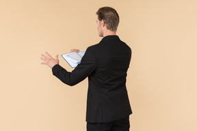 A white man in a fully black suit holding the quran