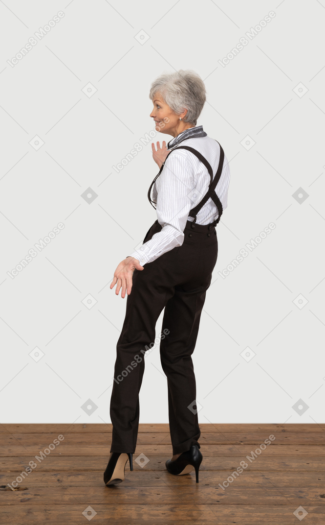 オフィス服でおかしい身振りで示す老婦人の背面図