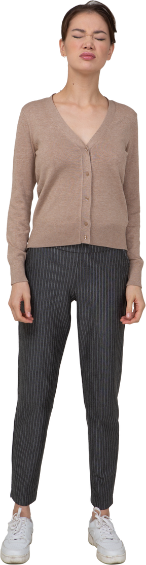 Vue de face d'une jeune femme en pull et pantalon debout avec les yeux fermés