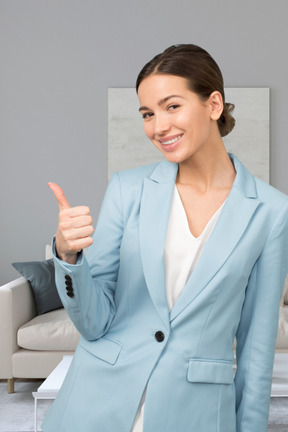 A woman in a blue suit giving a thumbs up