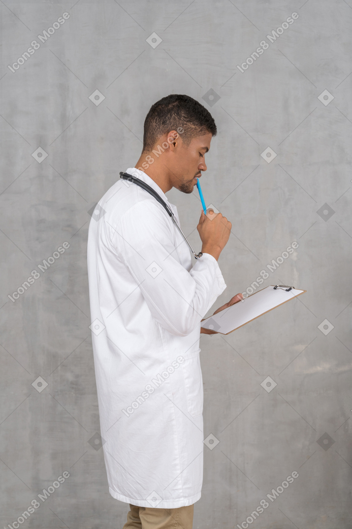 Vista lateral del joven médico tomando notas