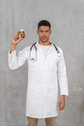 Male doctor in white lab coat holding a pill bottle