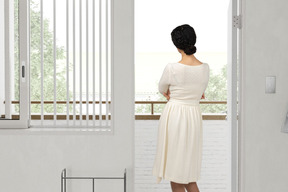 Back view of a woman in a white dress standing on a balcony