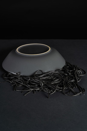 Flipped over plate with black pasta on dark background