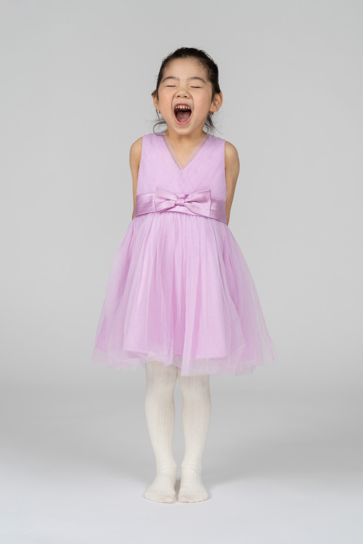 Front view of a little girl in a tutu dress yawning