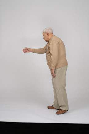 Vista laterale di un uomo anziano in abiti casual che dà una mano per scuotere