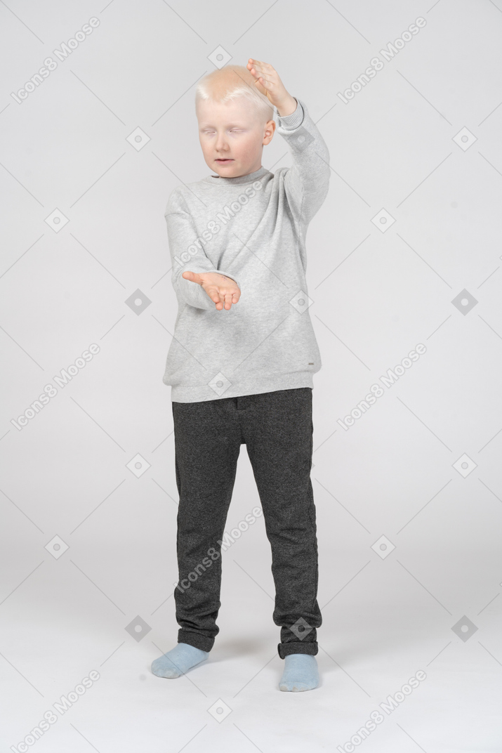 Boy with closed eyes showing the size of something with his hands