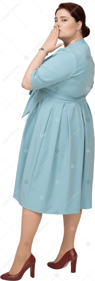 Vista lateral de uma mulher de vestido azul mandando um beijo