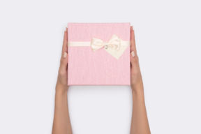 Female hands holding pink gift box