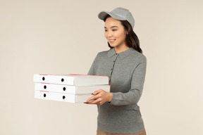 Garota de entrega de pizza asiática jovem segurando caixas de pizza