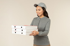 Young asian pizza delivery girl holding pizza boxes