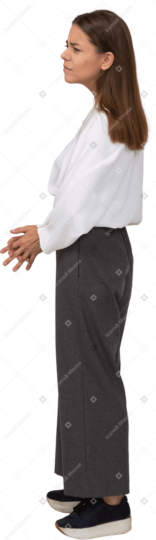 Side view of a confused young lady in office clothing holding hands together