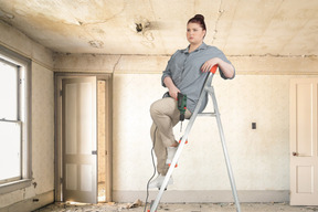 Woman sitting on a stepladder in the middle of the room