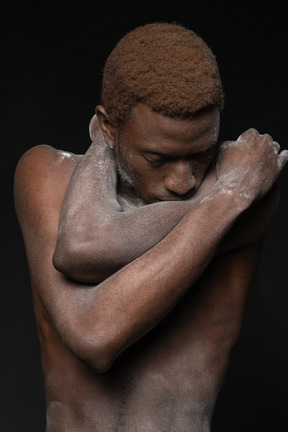 Close-up a young african manin the flour hugging himself