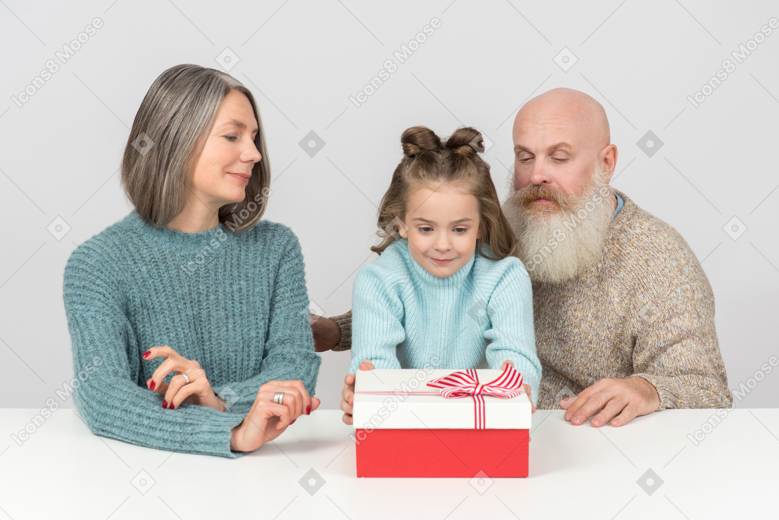 Kid girl sitting next to her grandparents and holding gift box
