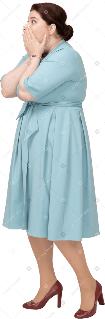 Side view of an impressed woman in blue dress covering mouth with hands