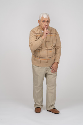 一位身穿休闲服的老人在做嘘手势的正面图