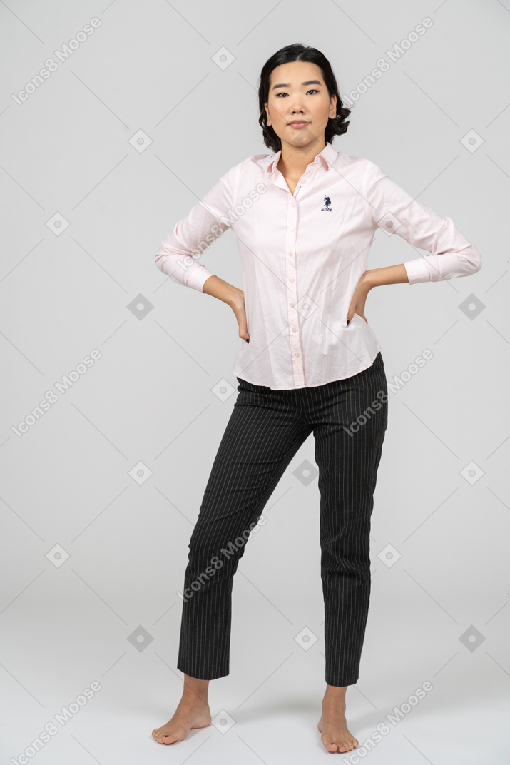 Женщина в офисной одежде позирует с руками на талии