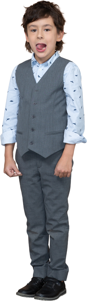 Front view of a cute boy in grey suit looking at camera and showing tongue