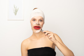 Young woman holding magnifier over her mouth