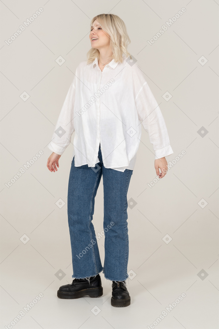 Front view of a blonde female in casual clothes outstretching arms and looking aside