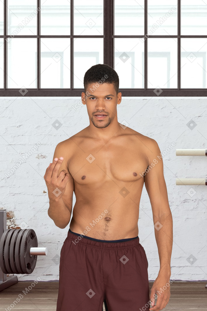 A shirtless man standing in a gym