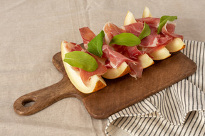 Aperitivo com melão fresco e presunto servido em uma placa de madeira