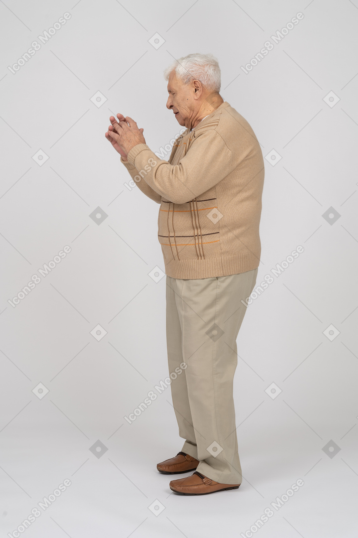 Side view of an old man in casual clothes dancing
