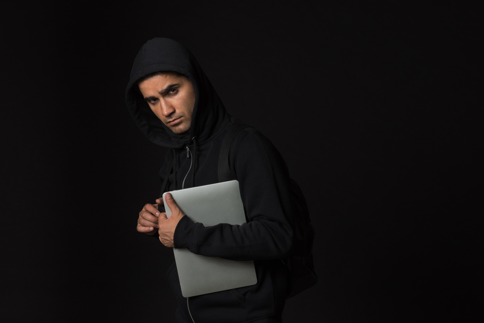Hacker guy standing in the dark and holding laptop