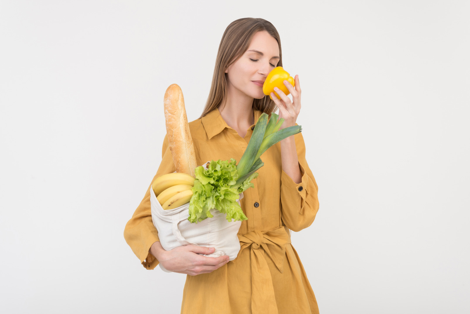 Young woman holding shopping bag and smelling a pepper out of it