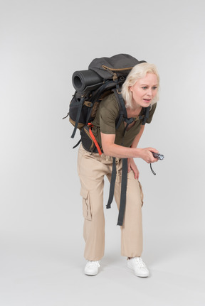 Carrying backpack mature female tourist using dictaphone