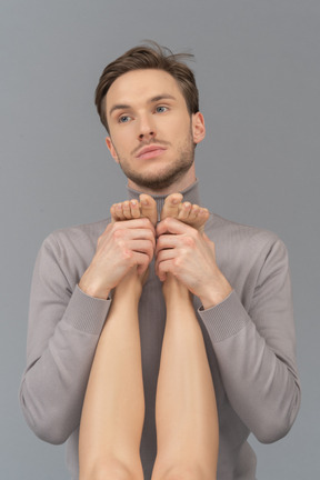 A thoughtful young man holding female`s feet