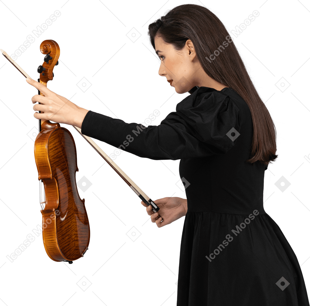 Side view of a female violin player in black dress making a bow