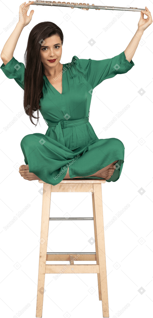 木製の椅子に座っている間、頭の上に彼女のクラリネットを保持している若い女性のフルレングス